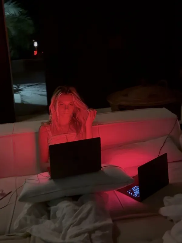 Nikki Neisler on a couch at night, lit by two laptops with red Sundown screens